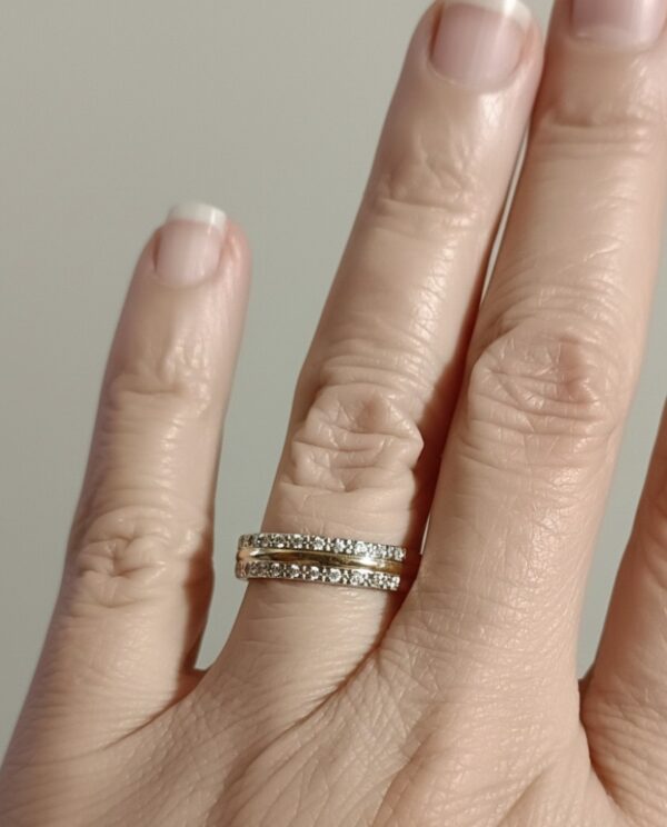 Kädessä 14K kultainen timanttisormus, jossa kaksirivinen timanttireunus.