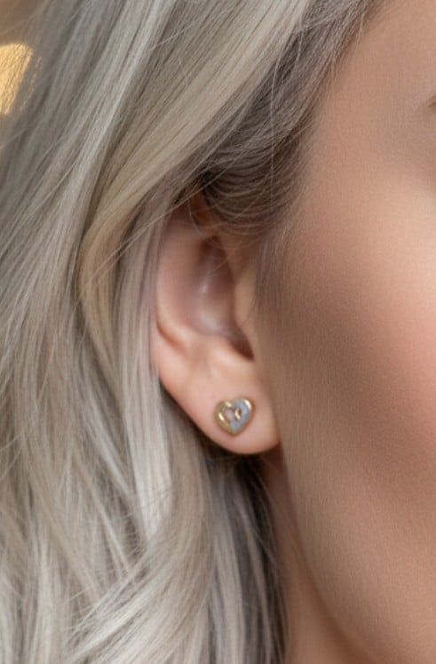 Nainen käyttää 14K kultaisia sydänkorvakoruja.