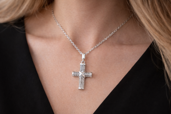 Näyttävä hopeinen ristiriipus zirkoniakivillä kaulassa